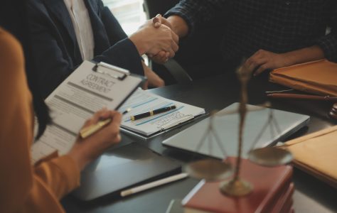Justice and Law concept. Legal counsel presents to the client a Justice and Law concept. Legal counsel presents to the client a signed contract with gavel and legal law or legal having team meeting at law firm in background